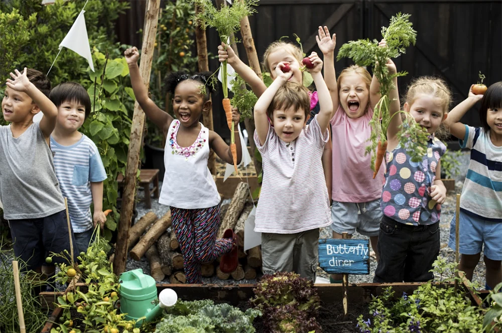 Kids with hands raised in a garden
